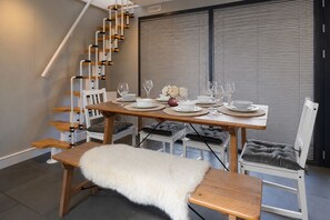 A dining area with a wooden table set for four, a bench with a fur throw, and a staircase with wooden steps. - Spacious Pet Friendly Home in Central Cheltenham. Sleeps 6 FREE Parking! (Cheltenham)