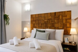 A hotel room with a wooden headboard, a bed with white bedding, two bedside lamps, and a small nightstand with a book. - Spacious Pet Friendly Home in Central Cheltenham. Sleeps 6 FREE Parking! (Cheltenham)