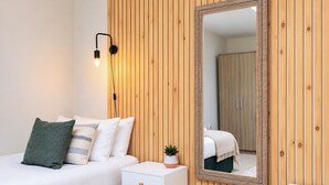 Une chambre à coucher comprenant un lit, une table de chevet, une lampe, un miroir et un mur recouvert de panneaux en bois.