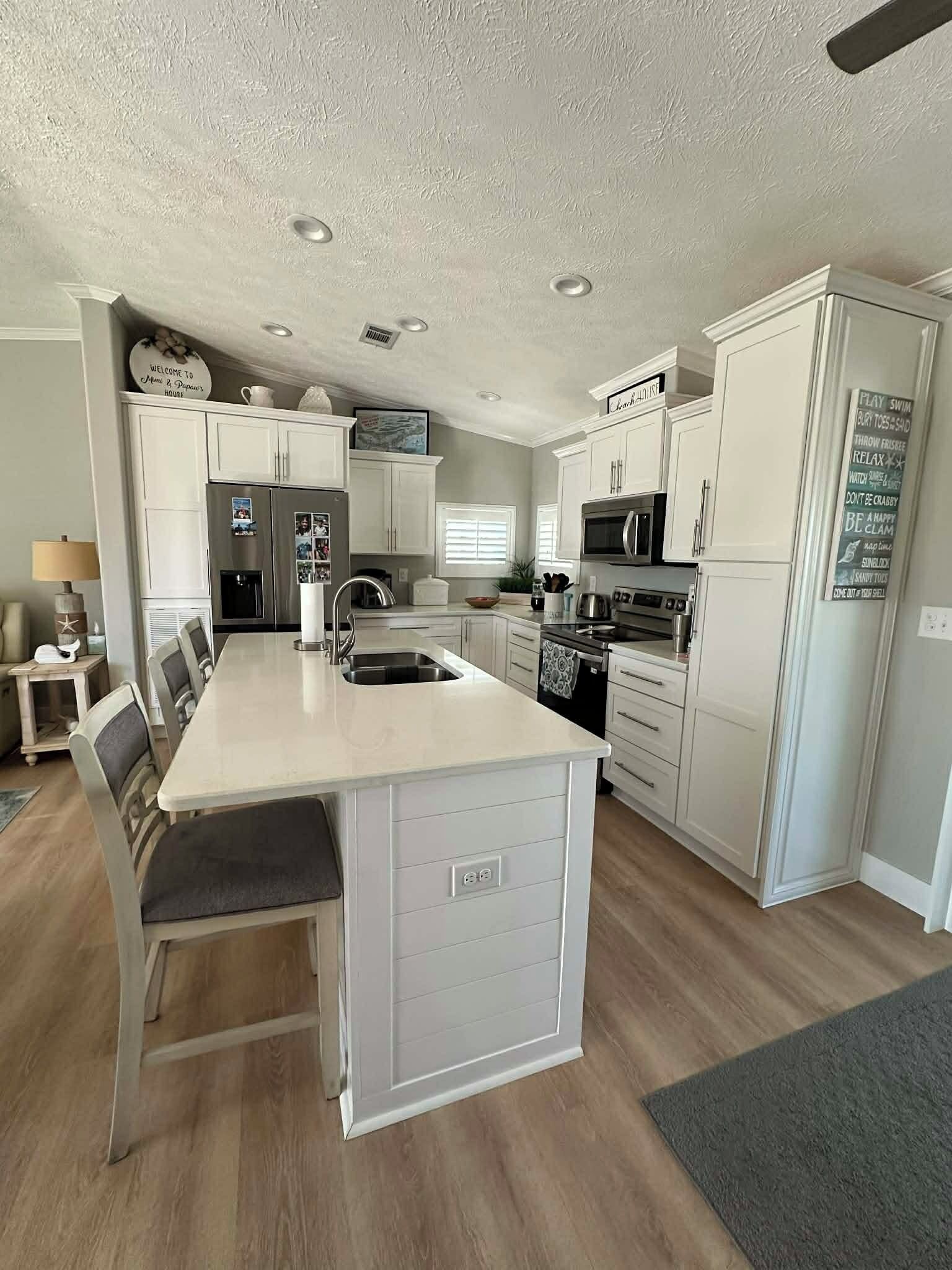 A modern kitchen with white cabinetry, a central island, a built-in oven, and a microwave.