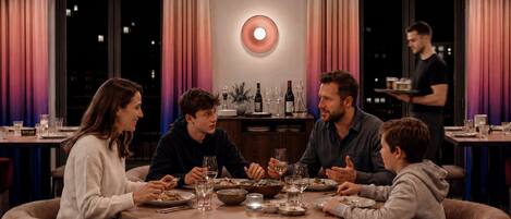 Una mesa redonda con copas de vino y un camarero.
