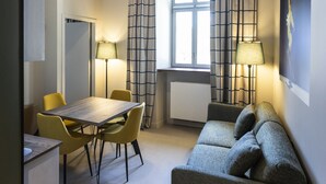 A room with a dining table, chairs, a sofa, a ceiling fan, and a window with curtains. - DAFFY Hôtel (Briançon)