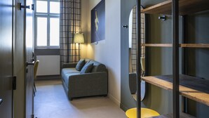 A modern interior with a sofa, a lamp, and a bookshelf. - DAFFY Hôtel (Briançon)