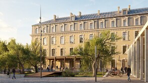 Edifici de diversos pisos d'estil arquitectònic clàssic, amb un pati central que compta amb arbres i un petit pont.