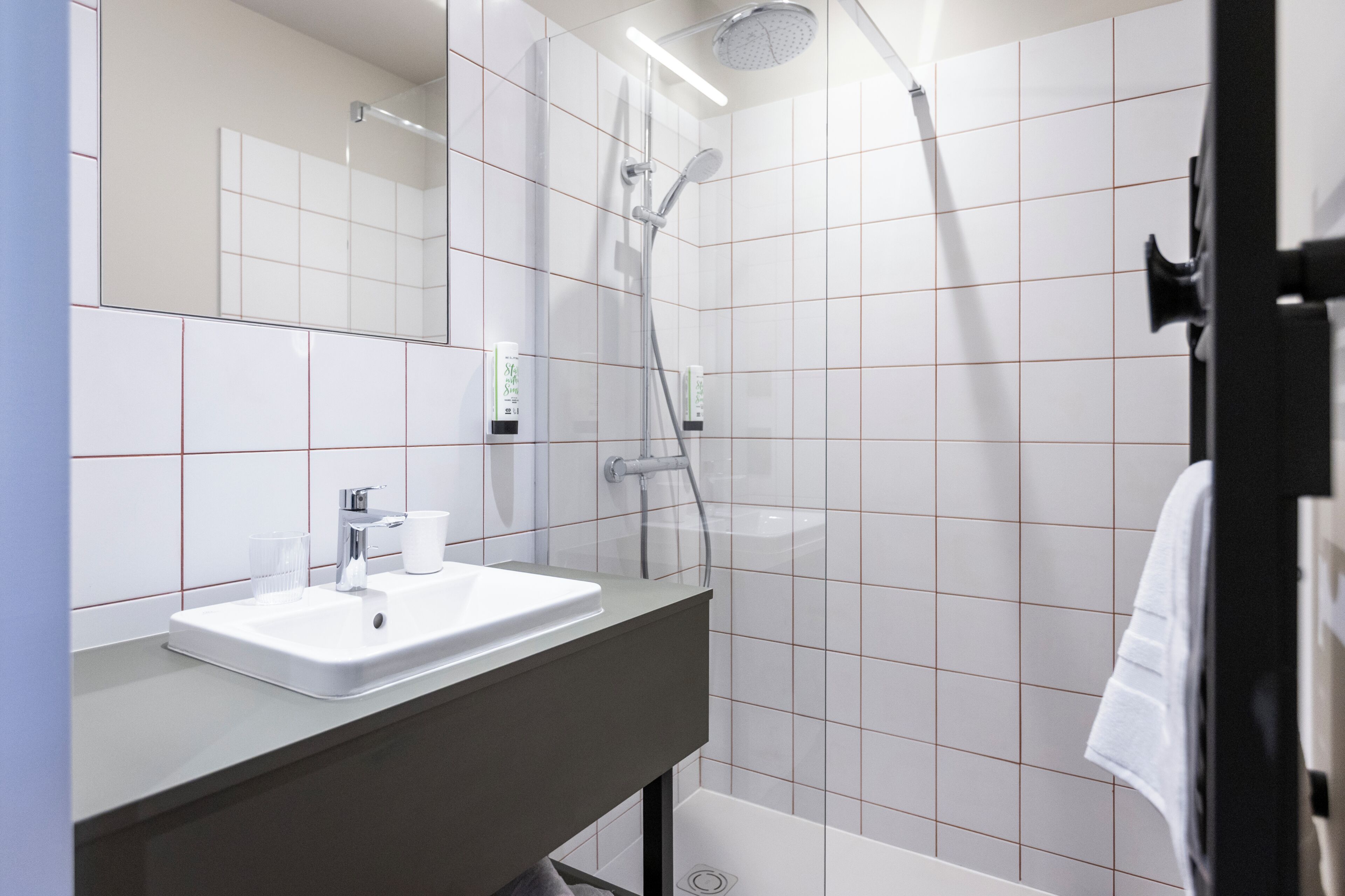 Un baño moderno con lavabo, espejo y ducha blancos.