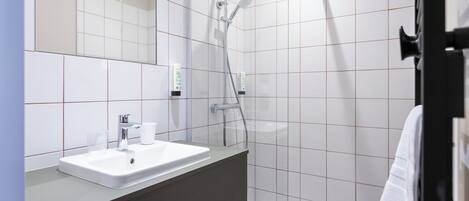 Un baño moderno con lavabo, espejo y ducha blancos.