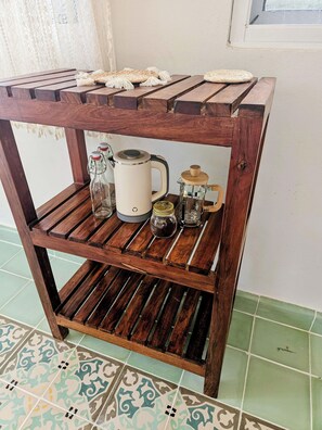 Ein Holztisch mit Regalen, einem Wasserkocher, einem Glasbehälter und einer kleinen Holzkiste.
