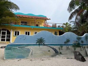 A beachside hotel with a large mural of a beach scene, palm trees, and a boat.