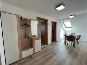 Ein Zimmer mit Kleiderschrank, Schreibtisch und Esstisch.