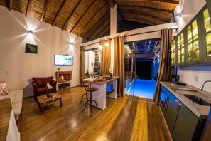 A cozy living area with a fireplace, a dining table, and a kitchen with a view to the outside.