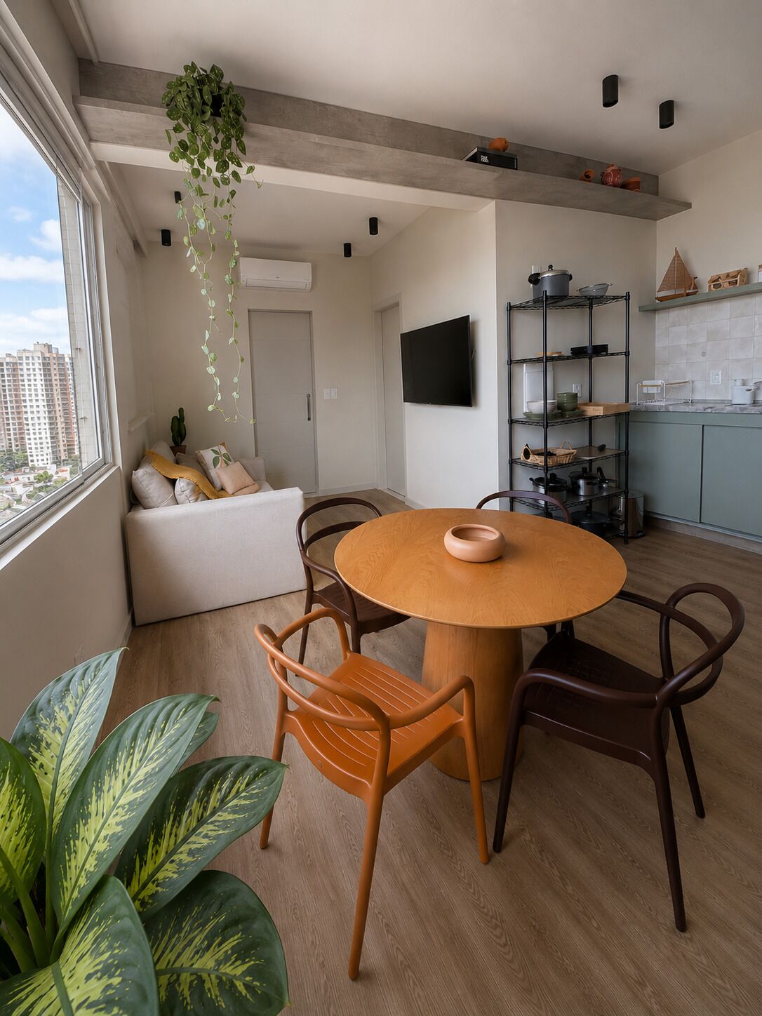 A modern living room with a round wooden table, two chairs, a sofa, and a TV.