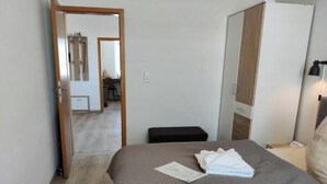 Een hotelkamer met een bed, een bankje, een garderobe en een spiegel.