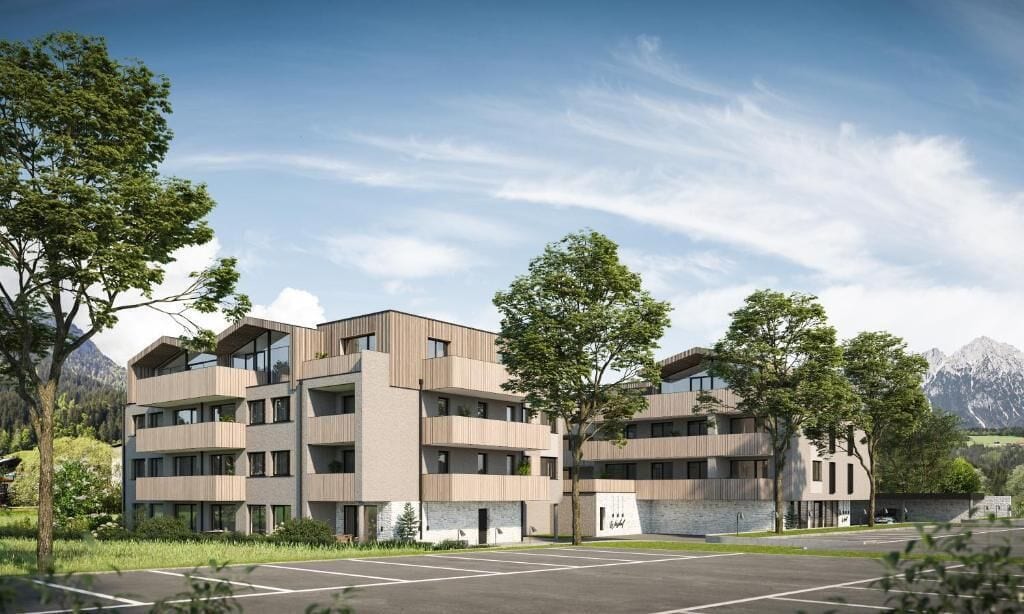 A multi-story building with a modern architectural design, featuring balconies and a parking area in front.