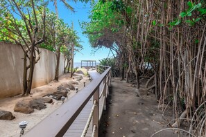 A pathway with a wooden railing, surrounded by trees and a concrete wall. - Cozy Island-Style Villa - 2 minute walk from beach (Beach)