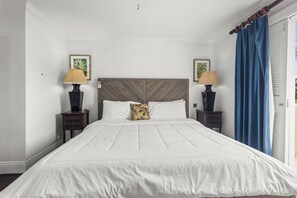 A bedroom with a large bed, two nightstands, a wooden headboard, and two wall-mounted lamps. - Cozy Island-Style Villa - 2 minute walk from beach (Beach)