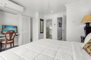 Une chambre à coucher comprenant un lit, un bureau, une chaise, un téléviseur et un appareil de climatisation.