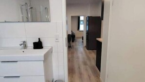 Een moderne keuken met witte kasten, een spoelbak en een vuilnisbak.