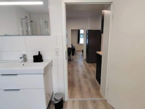 A modern kitchen with white cabinets, a sink, and a trash bin. - Feel-good apartment in the heart of Clausthal (Clausthal-Zellerfeld)