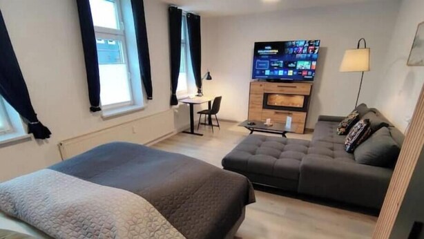 Een hotelkamer met een bed, een slaapbank, een televisie en een bureau.