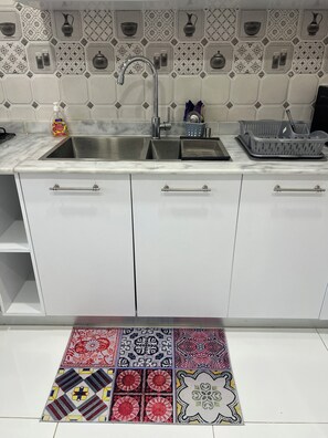 Una cocina con un lavamanos doble, armarios blancos y un salpicadero con diseño.