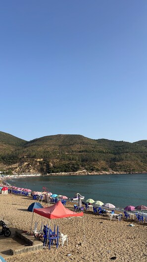 Een strand met tenten, stoelen en parasols.