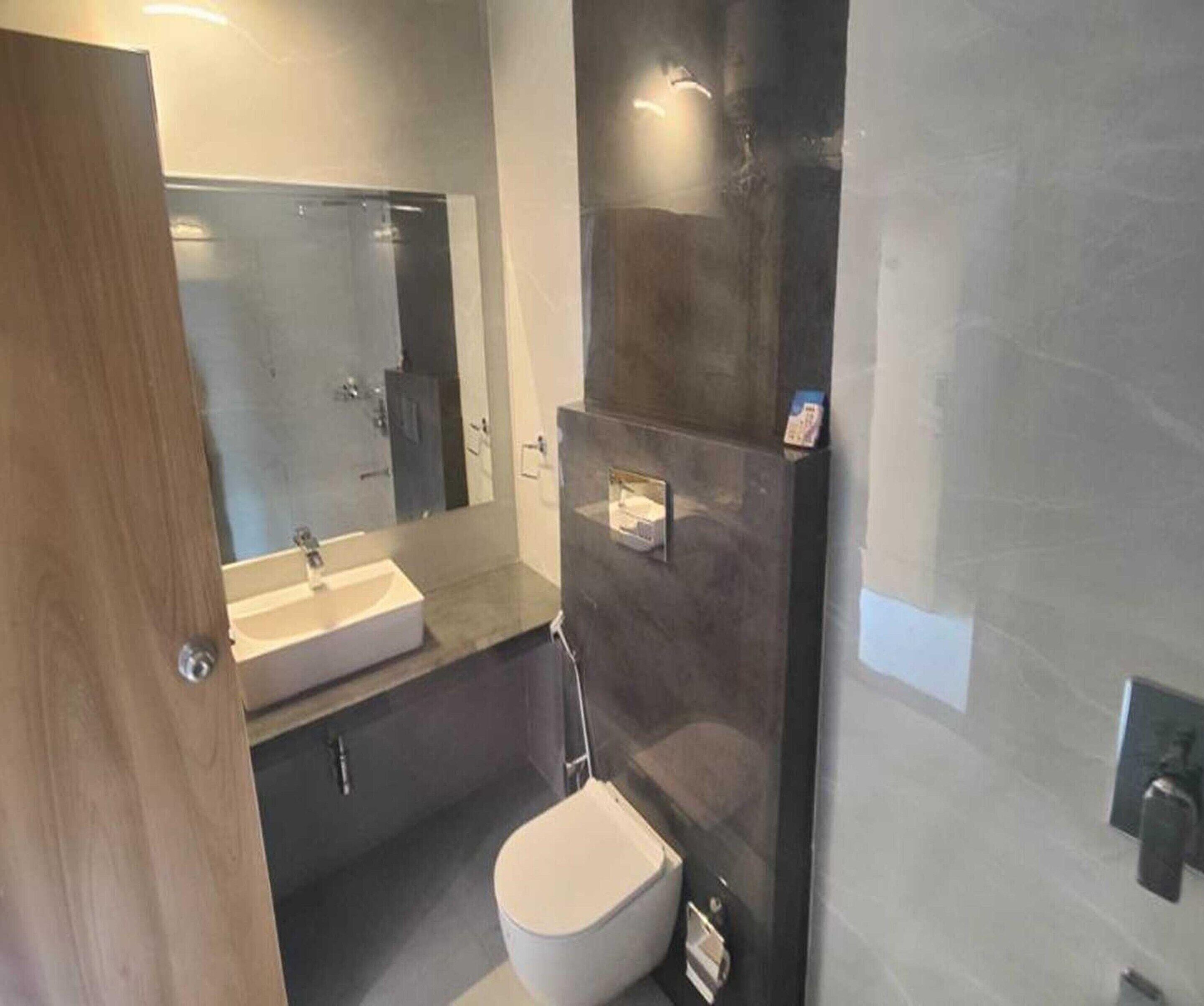 A bathroom with a white sink, a mirror, a toilet, and a shower area.