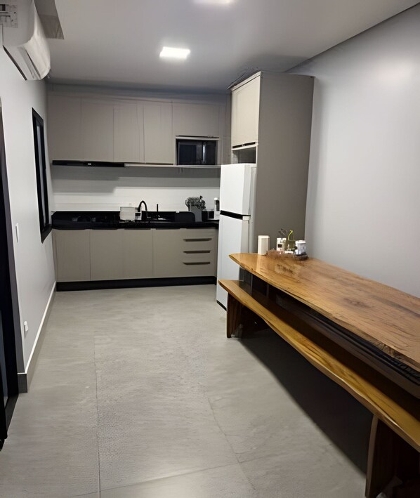 Una cocina moderna con armarios blancos, encimera negra y banco de madera.