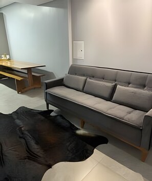 Una sala de estar moderna con un sofá gris, una mesa de centro de madera y un tapete de diseño blanco y negro.