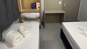 Een hotelkamer met twee bedden, een kledingkast, een bureau en een deur.