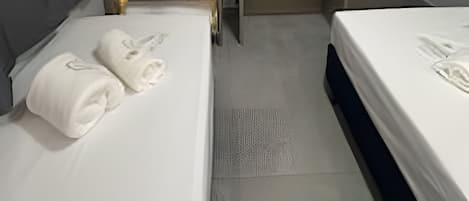 Une chambre d’hôtel avec deux lits, une armoire, un bureau et une porte.