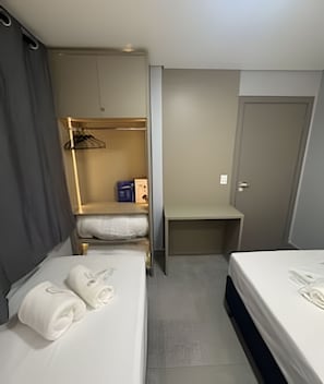 Une chambre d’hôtel avec deux lits, une armoire, un bureau et une porte.