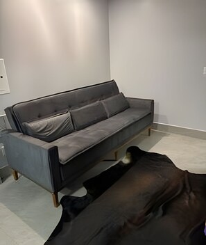 A modern living room with a grey sofa, a coffee table, and a small rug. - Casa Confortavel em Foz do Iguaçu (Foz do Iguaçu)