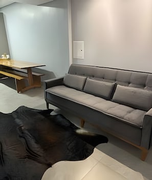 Un salon moderne avec un canapé gris, une table basse en bois et un tapis aux motifs noir et blanc.
