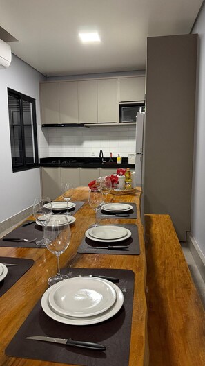 A modern kitchen with a dining area set for a meal. - Casa Confortavel em Foz do Iguaçu (Foz do Iguaçu)