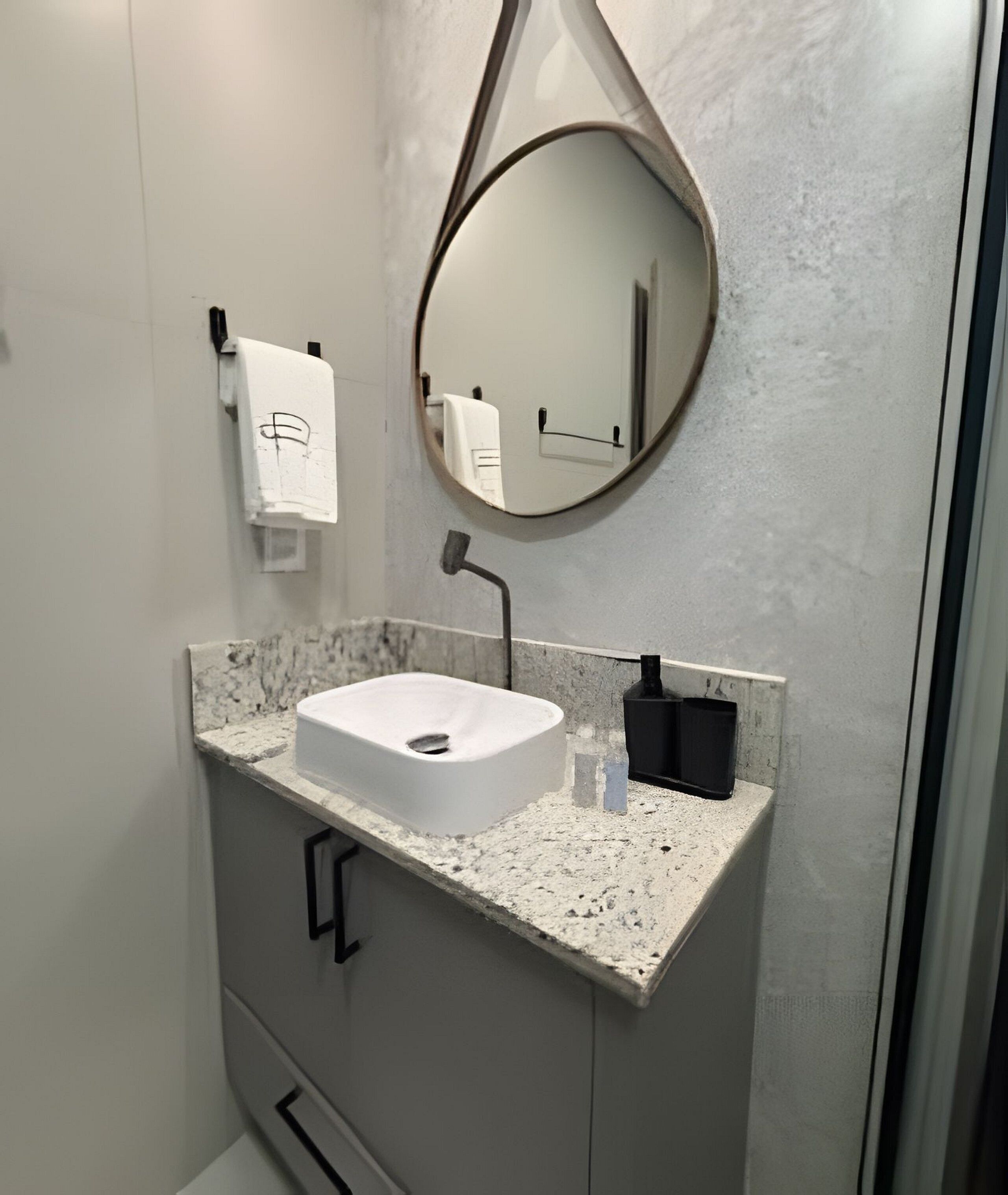 A bathroom with a white sink, a round mirror, and a towel hanging on a rack.