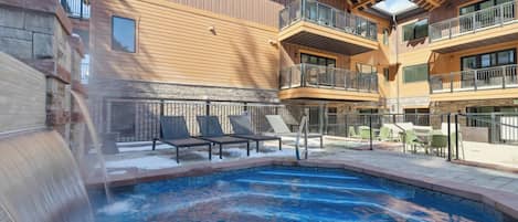 Um hotel com área de piscina, mobiliário para áreas externas e uma cascata.