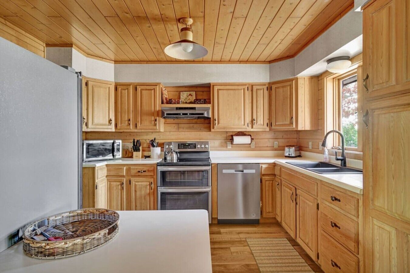 Cocina con gabinetes de madera, microondas, estufa, horno y lavavajillas.
