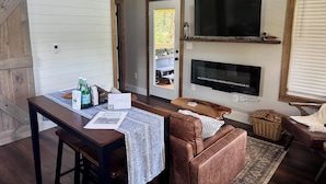 Une pièce chaleureuse avec une table en bois, un canapé, un téléviseur et une cheminée.
