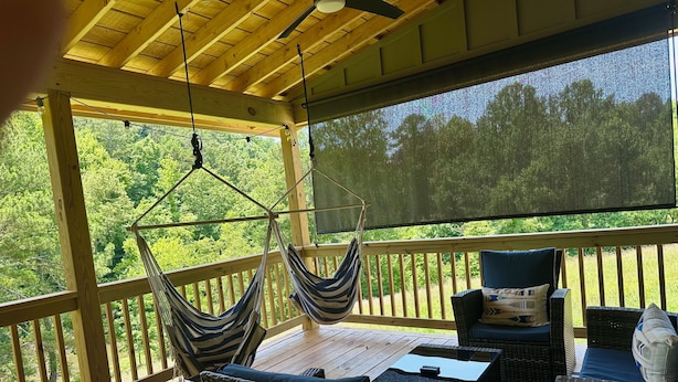 Une terrasse extérieure couverte, aménagée avec des meubles en osier, un hamac et offrant une vue sur la forêt.