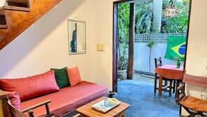 A room with a red sofa, wooden table, and chairs, a staircase, and a view of greenery outside. - Oceana Suites Veralucia (Tibau do Sul)