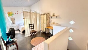 A room with a bed, a chair, a table, a fan, and a curtain. - Oceana Suites Veralucia (Tibau do Sul)