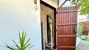 A wooden gate, a potted plant, and a doorway with a decorative curtain. - Oceana Suites Veralucia (Tibau do Sul)