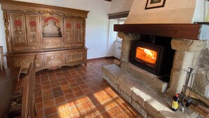 Un interior rústico con chimenea de piedra, muebles de madera y suelo de baldosas.