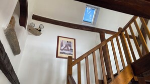 Una escalera de madera con un muro de piedra y un cuadro enmarcado.
