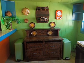 A kitchen with a wooden counter, a coffee grinder, decorative plates, and a clock.