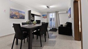 A modern dining area with a black table and chairs, a black sofa, and a window with curtains. - Spacious 2BR Podium Marina near Valletta (Msida)