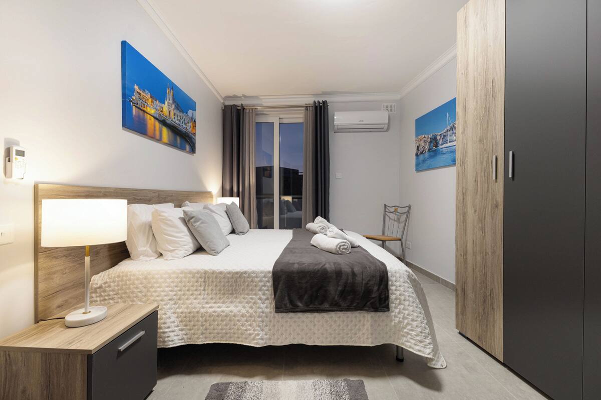 A neatly arranged hotel room with a bed, bedside lamp, and artwork on the walls.