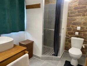 Et badeværelse med bruser, toilet og vask.