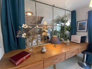 Et træbord med en lampe, en tepotte og en rød æske.