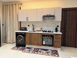 A compact kitchen with a washing machine, oven, and a toaster. - Steps to the Beach. NEW 1BR with Garage & Netflix (Kenitra)